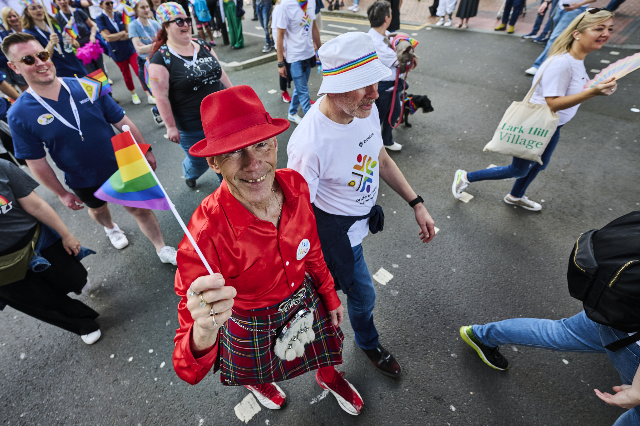 Two individuals in hats waving a pride flag.