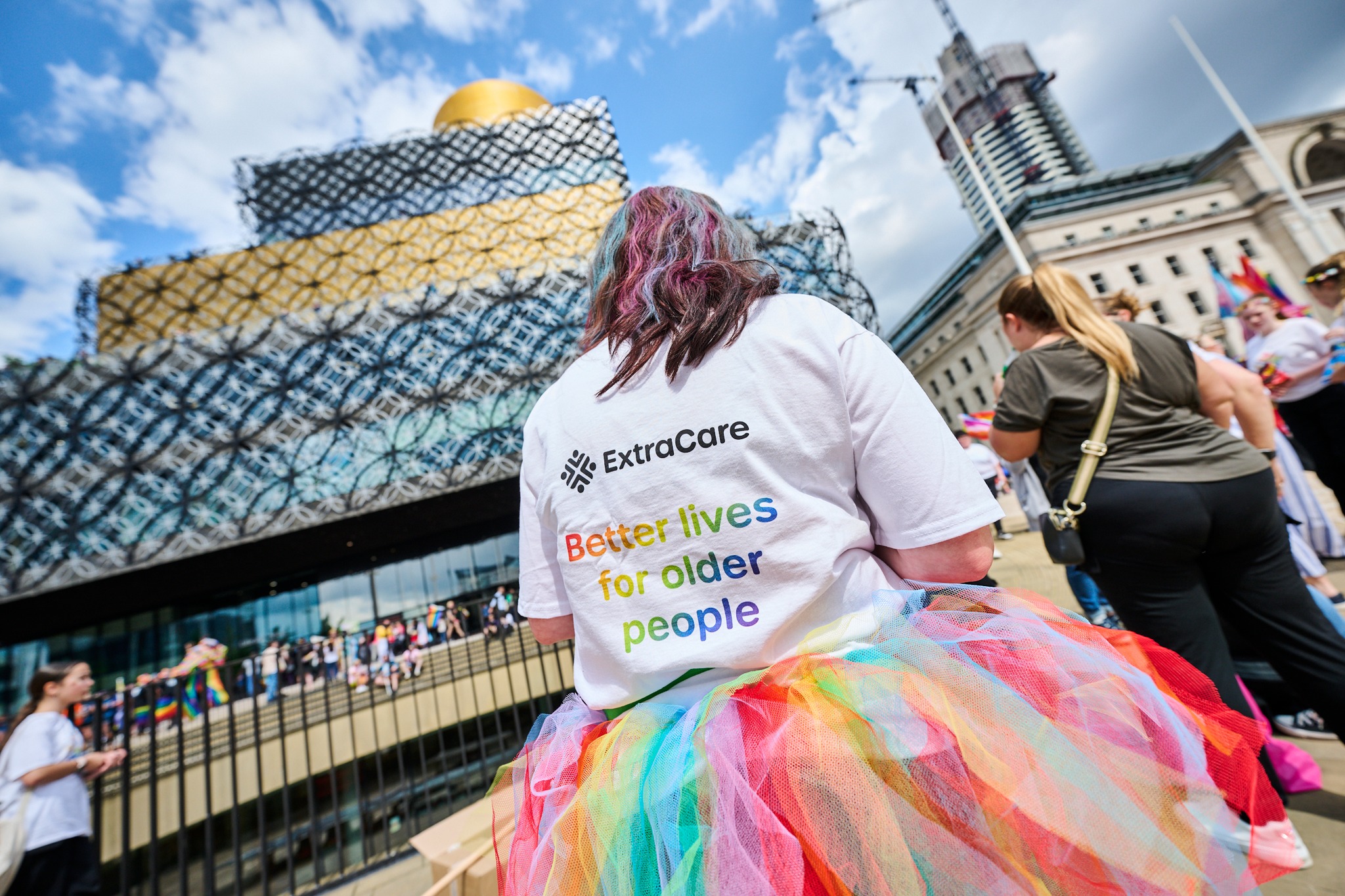 A pride attendee shows off the back of her tshirt with the extracare strapline on it.