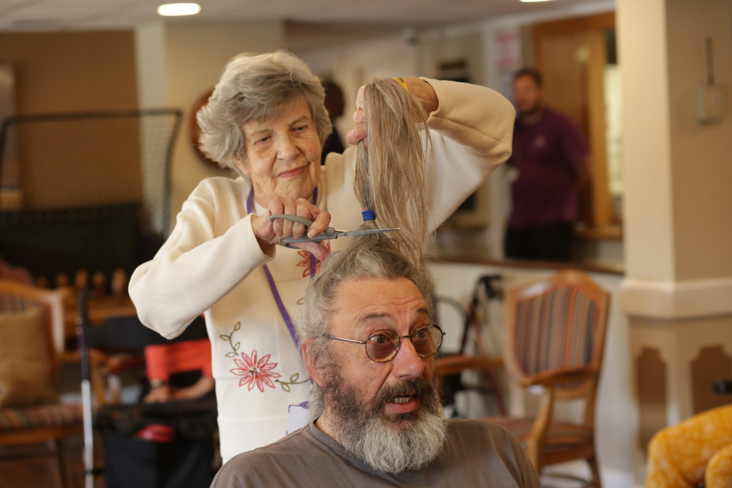 Margaret cutting Gary's hair with scissors.