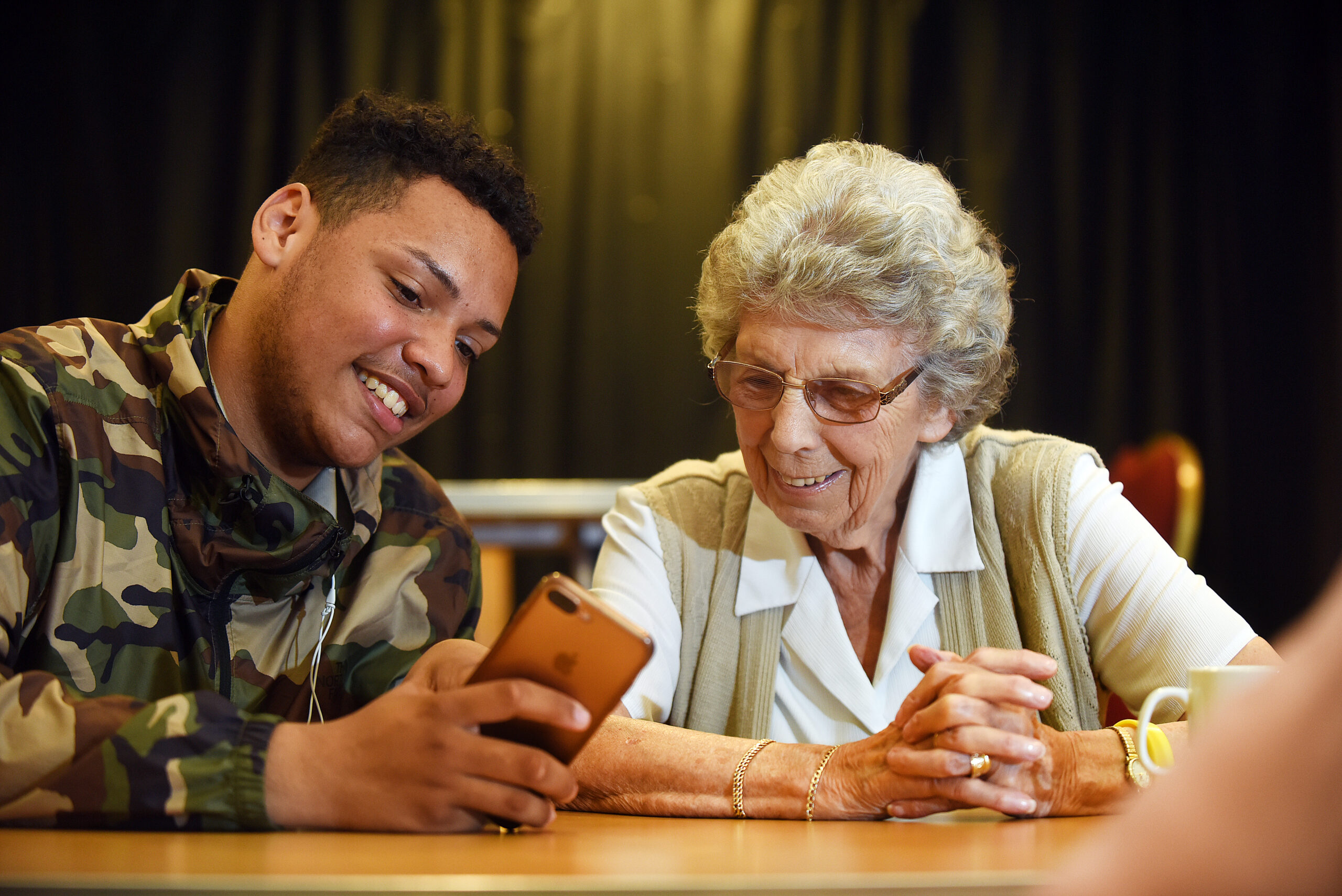 A young person showing a phone to an older lady.