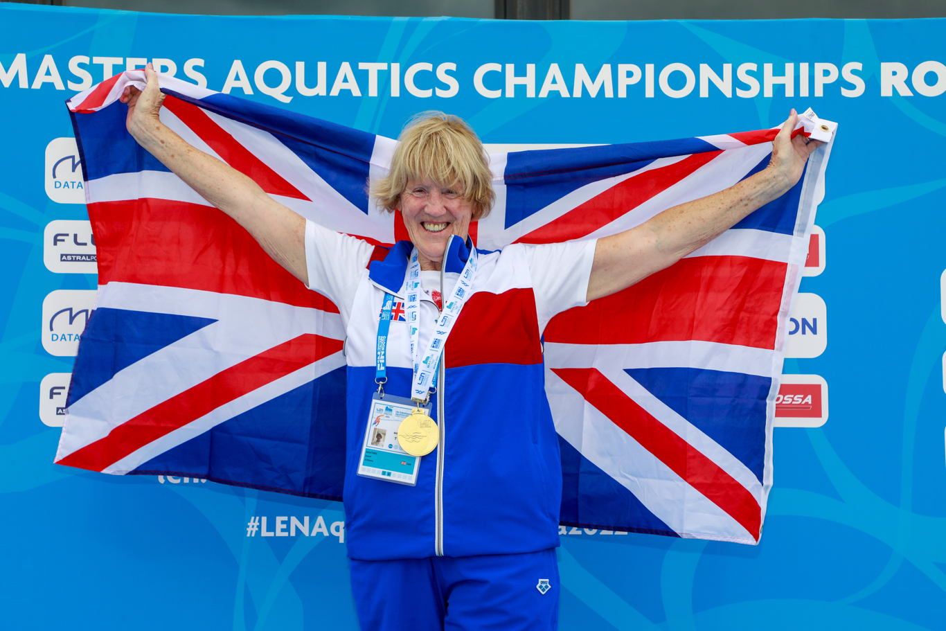 Janet stood with a union jack flag behind her and a medal on.